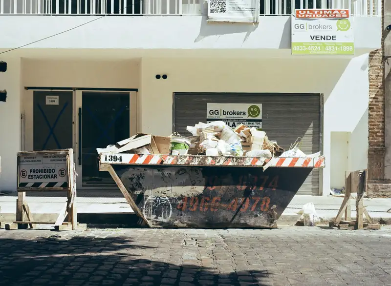 Benne à gravats remplie devant une façade en travaux