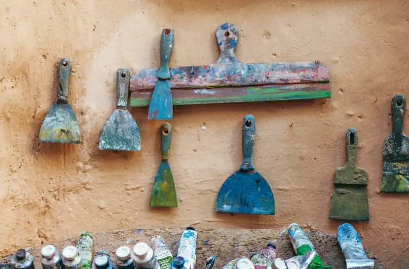 Couteaux à enduire et spatules accrochés à un mur enduit
