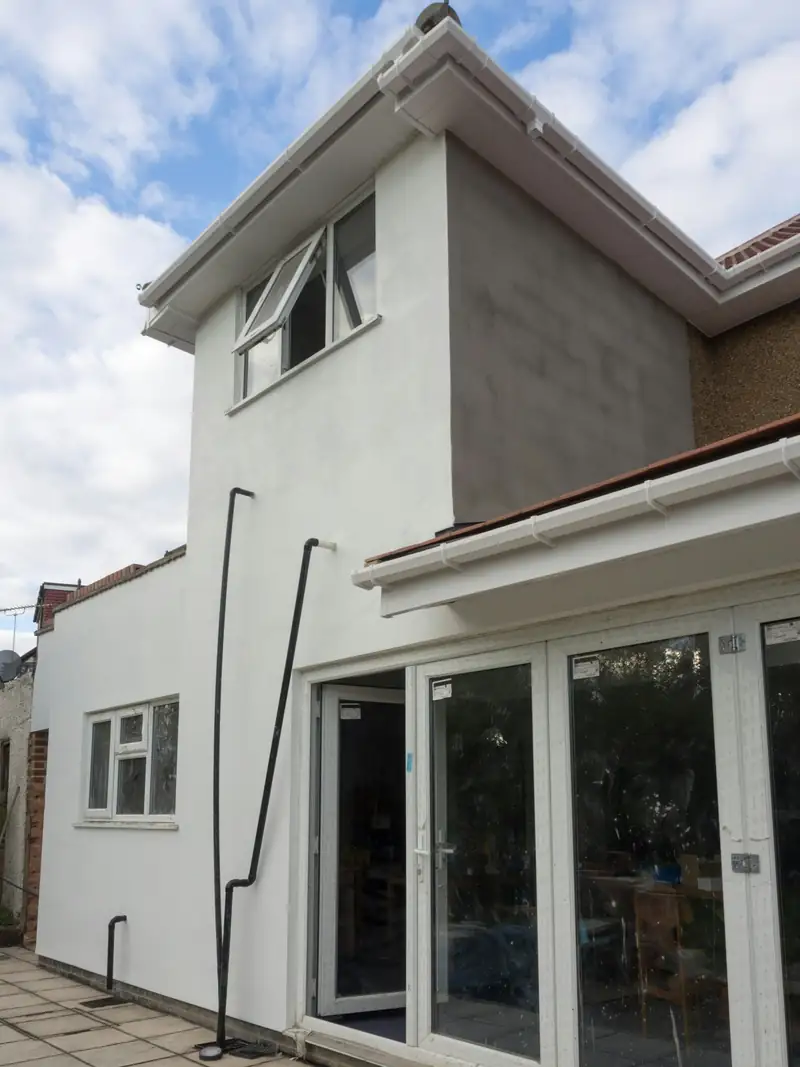 Maison prolongée par une extension enduite de blanc, portes-fenêtres sur le jardin