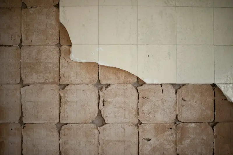 Mur après la dépose d’une faïence : traces de colle et carreaux restants