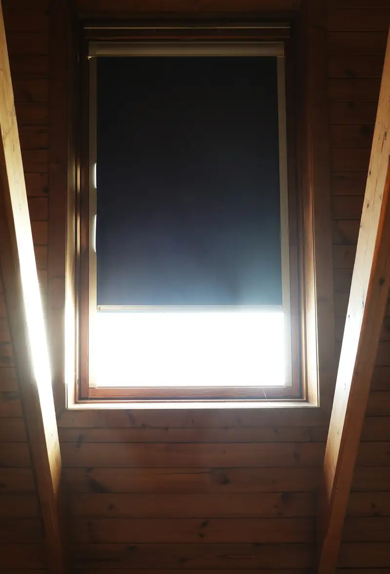 Fenêtre de toit encadrée de bois, lumière vive dans les combles