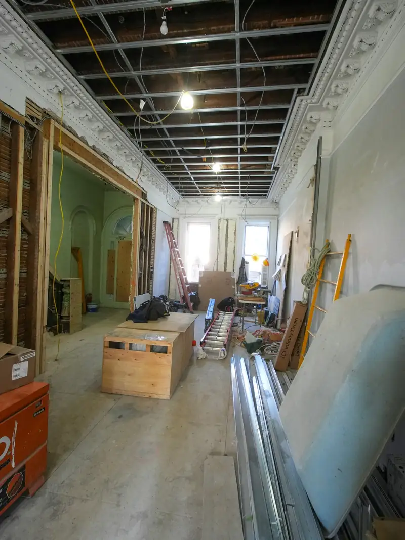 Pièce en rénovation : plafond ouvert, matériaux et outillage au sol