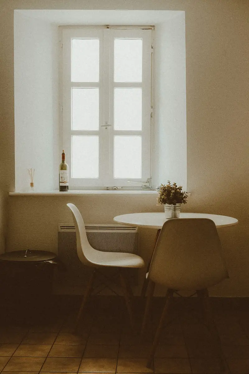 Table ronde et chaises près d’une fenêtre, lumière douce du matin